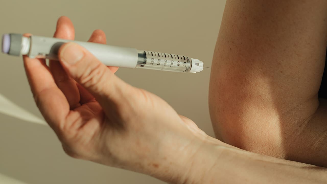 Close-up of a GLP-1 injection pen being administered for weight management