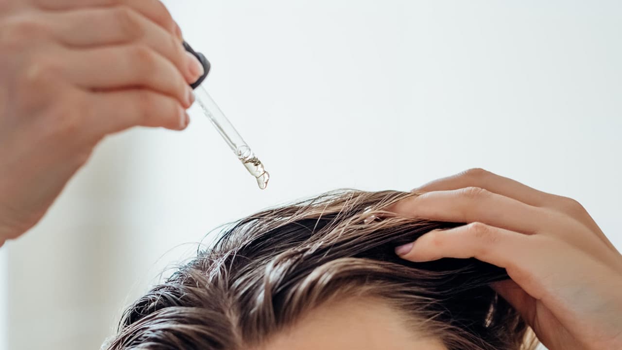 Person applying hair loss treatment serum to scalp